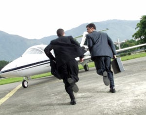 Two businessman running towards a plane.
